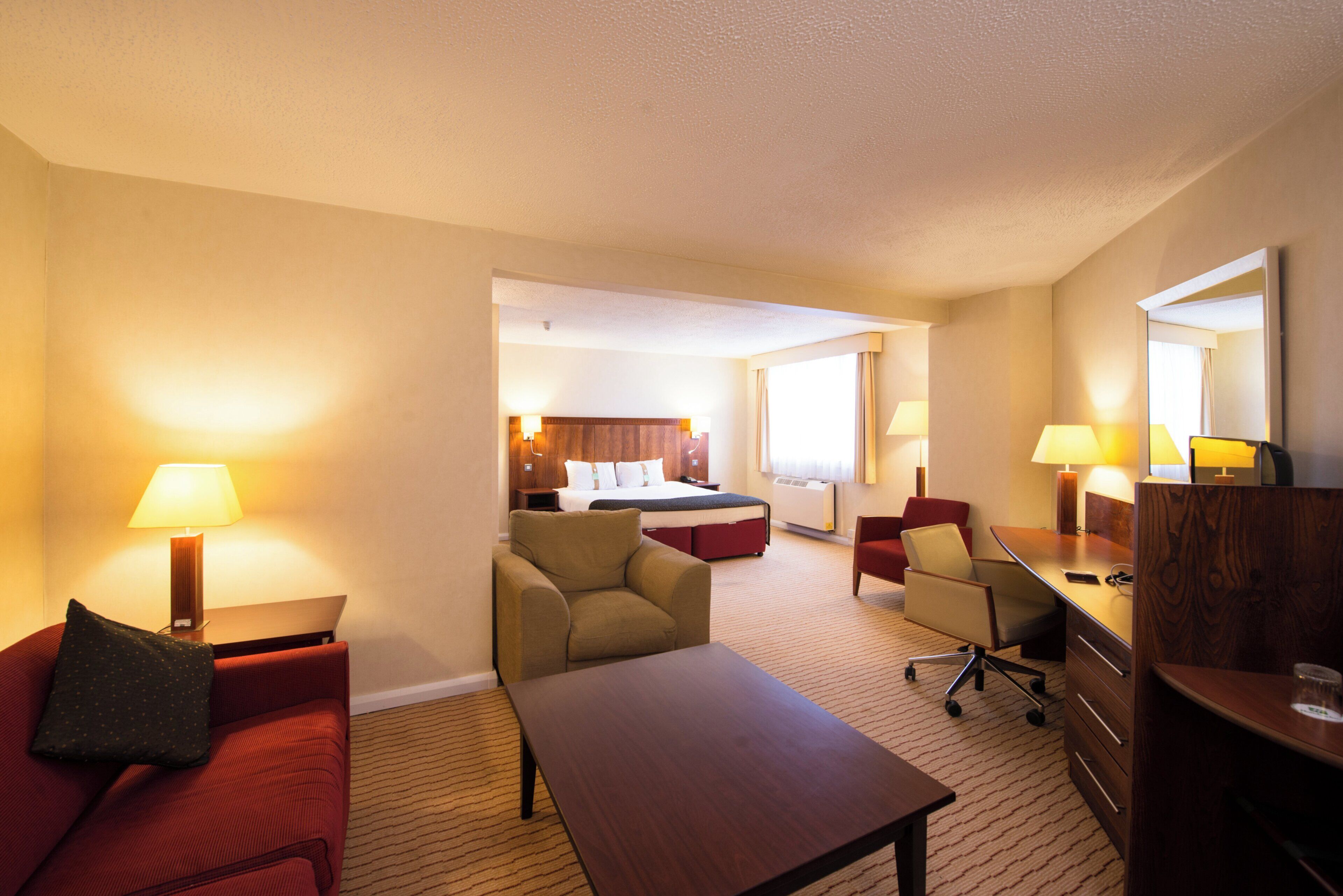 Habitación de hotel con cama, dos sillones, un escritorio y un aparador.