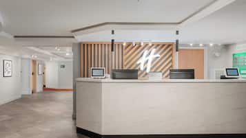 Un mostrador de recepción moderno con una pantalla grande, un panel de pared de madera y una pantalla digital.