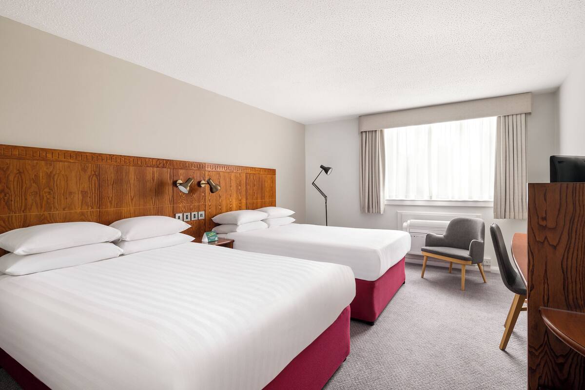 Una habitación de hotel con dos camas, un escritorio, una silla y un televisor.