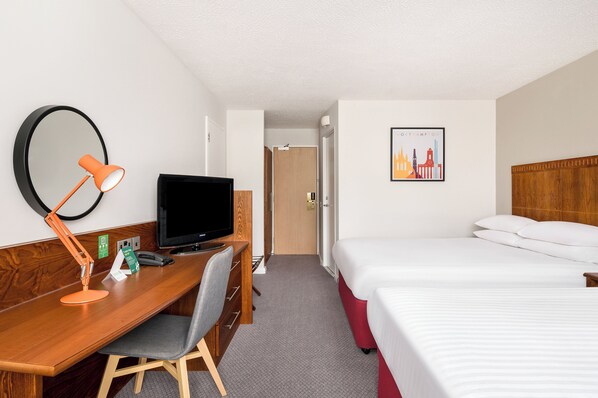 A hotel room with a wooden desk, a television, a bed, and a framed picture on the wall. - Holiday Inn Northampton by IHG (Northampton)