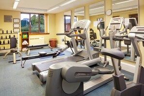 A gym with cardio machines, weightlifting equipment, and a window with a view of greenery.