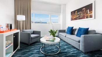 A staircase with a white railing, a white chair, and a shelf with decorative items. at YVE Hotel Miami