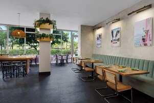 Un ristorante con posti a sedere interni, ampie finestre e opere d'arte alle pareti.