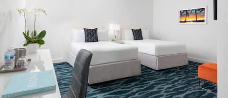 A hotel room with a bed, a desk with a book, a plant, and a painting on the wall.