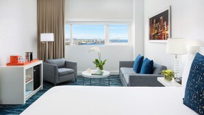 A hotel room with a bed, two sofas, a coffee table, a TV, and a window with a city view. - YVE Hotel Miami (Miami)