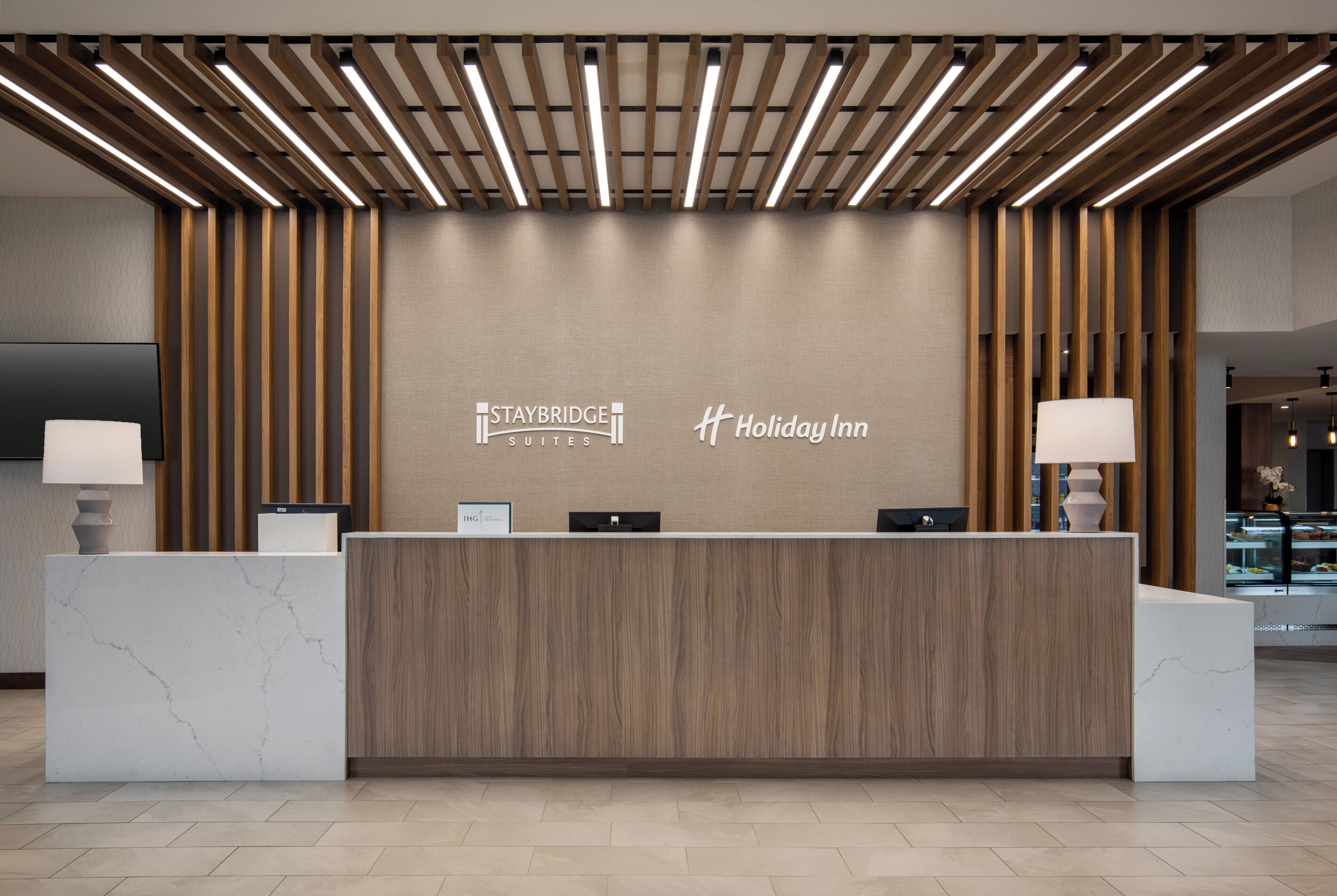 En receptionsdisk med en marmorskiva och träpanel, där logotyperna för Staybridge Suites och Holiday Inn syns.