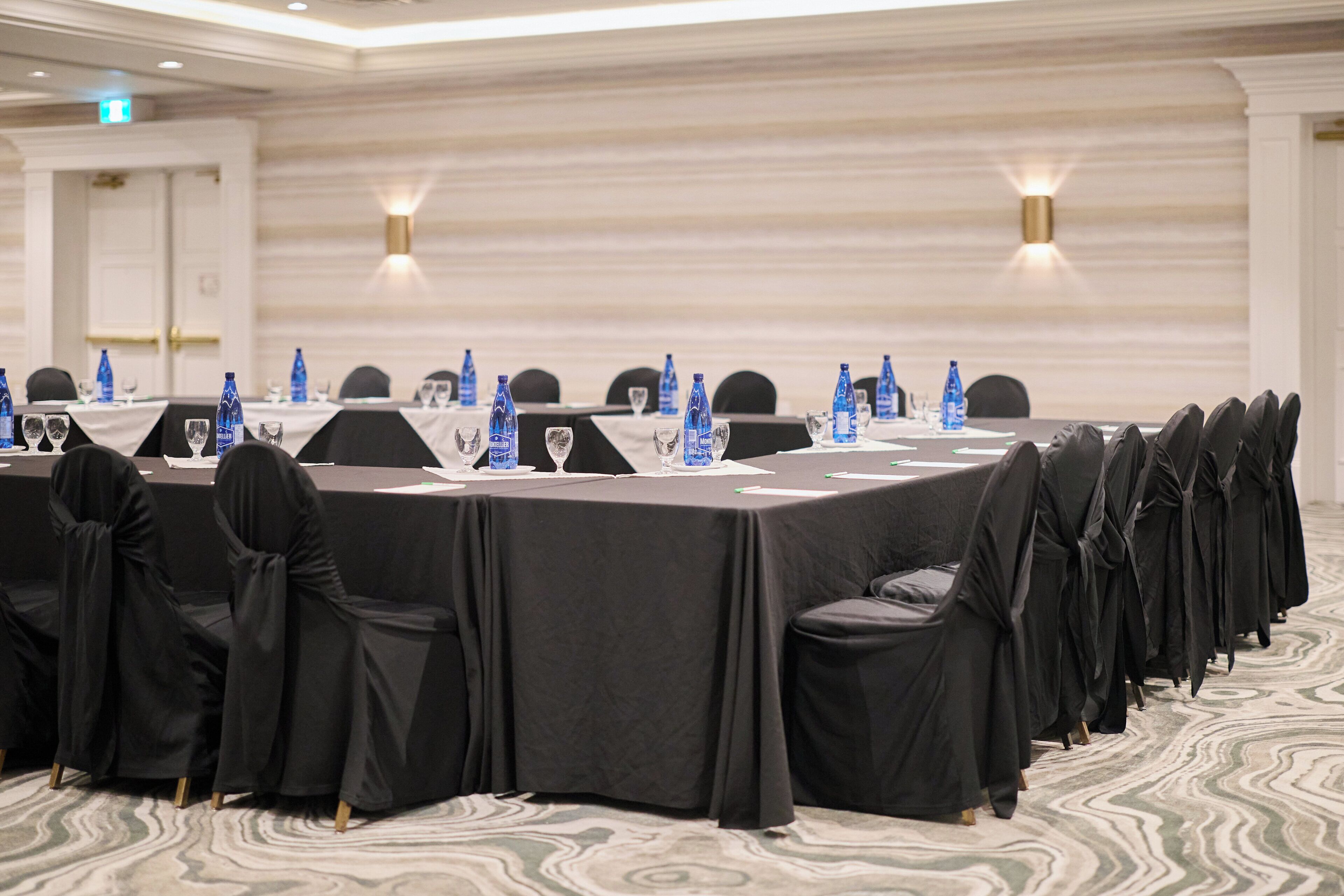 Una sala de conferencias con una larga mesa, sillas, botellas de agua y vasos.