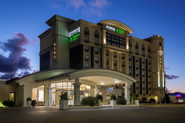 Un hotel grande con un cartel visible de Staybridge, un letrero de Holiday Inn & Suites, y una entrada bien iluminada con un corredor cubierto.