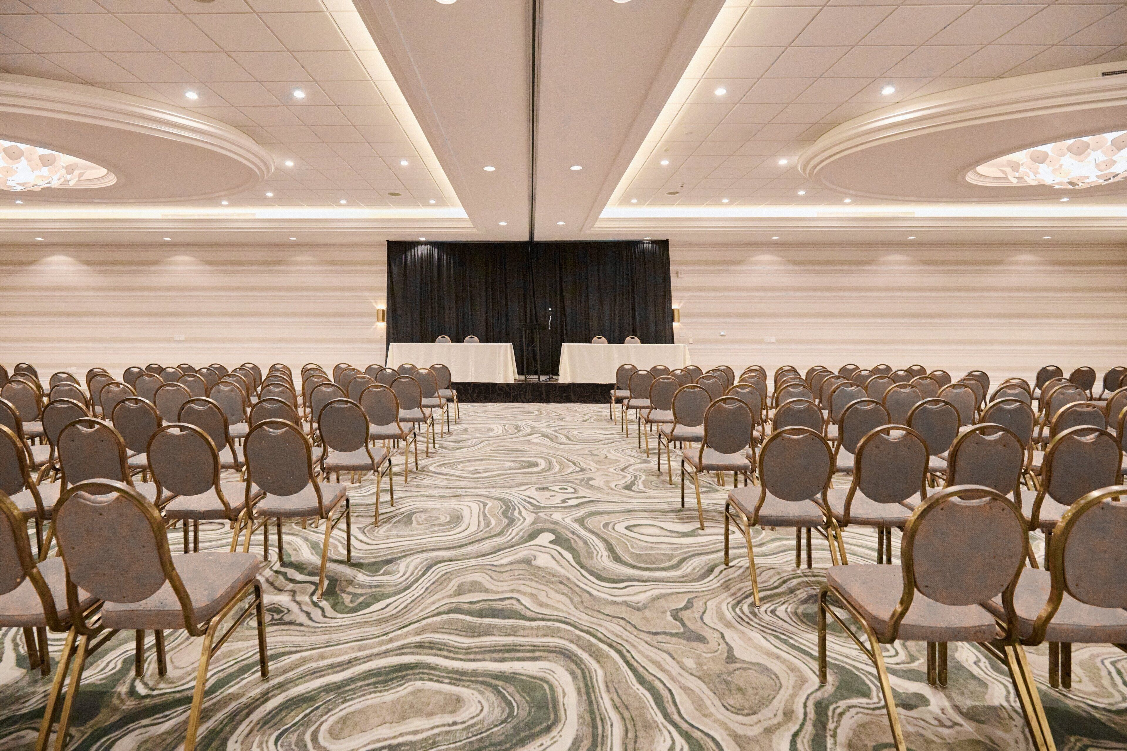 A conference room with rows of chairs facing a stage with a podium.