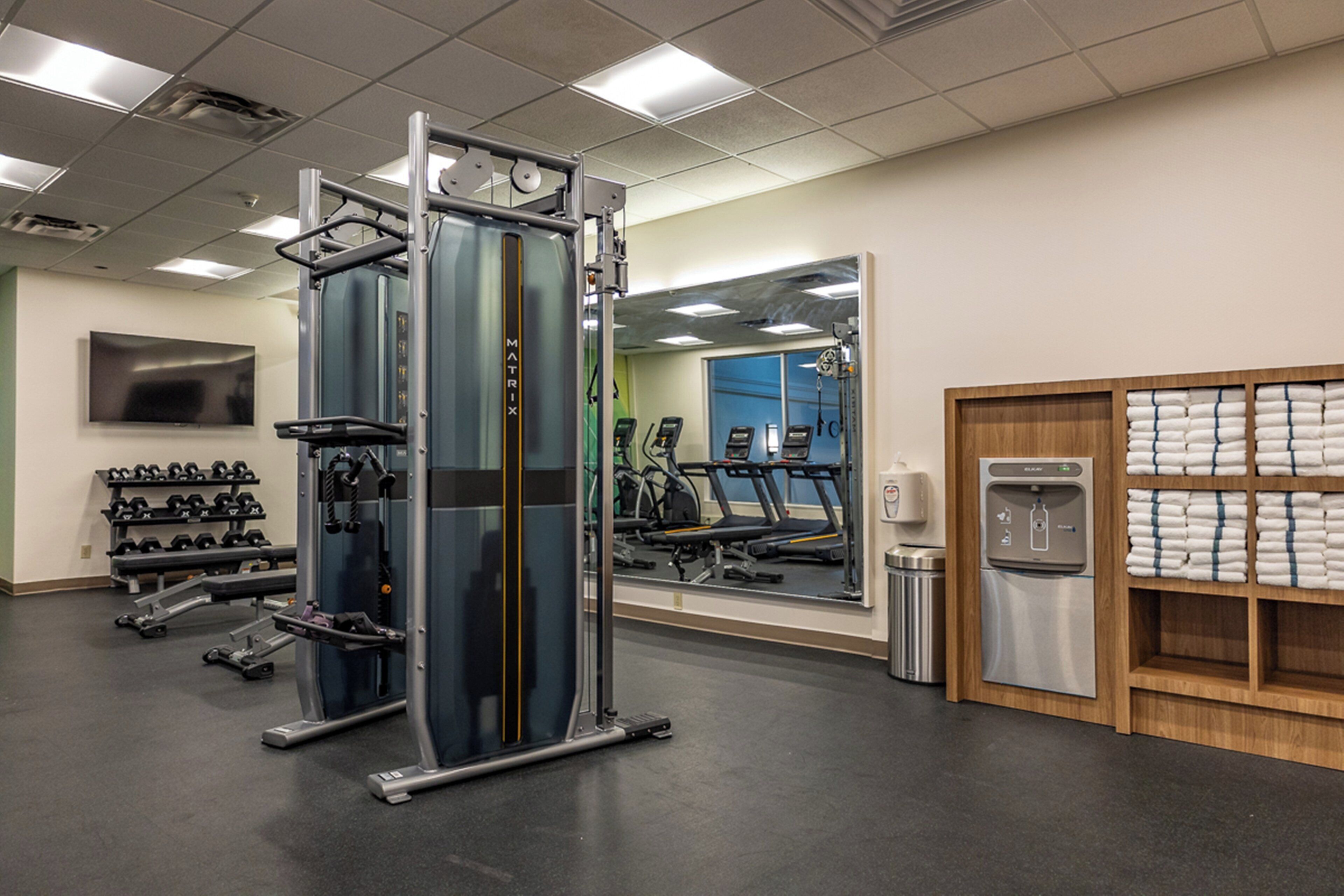 A gym with exercise equipment, a water dispenser, and a mirror.