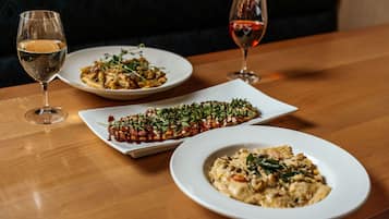 Uma mesa com três pratos e duas taças de vinho.