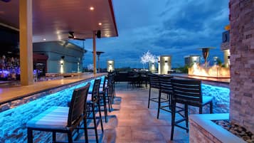 Zona de bar al aire libre con asientos y vista a la piscina.