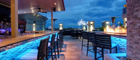 Zona de bar al aire libre con asientos y vista a la piscina.
