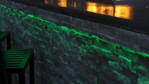 A stone wall with a fire feature and green lighting.
