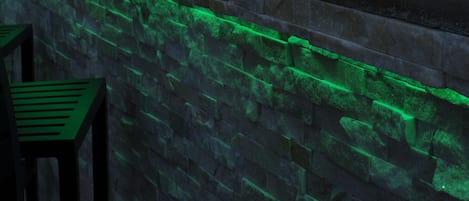 Una pared de piedra con una chimenea y luces verdes.