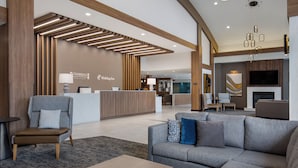 A modern hotel lobby with a reception desk, seating area, and a fireplace. - Holiday Inn Hotel & Suites St. Catharines Conference Center by IHG (St. Catharines)