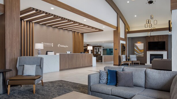 A modern hotel lobby with a reception desk, seating area, and a fireplace.