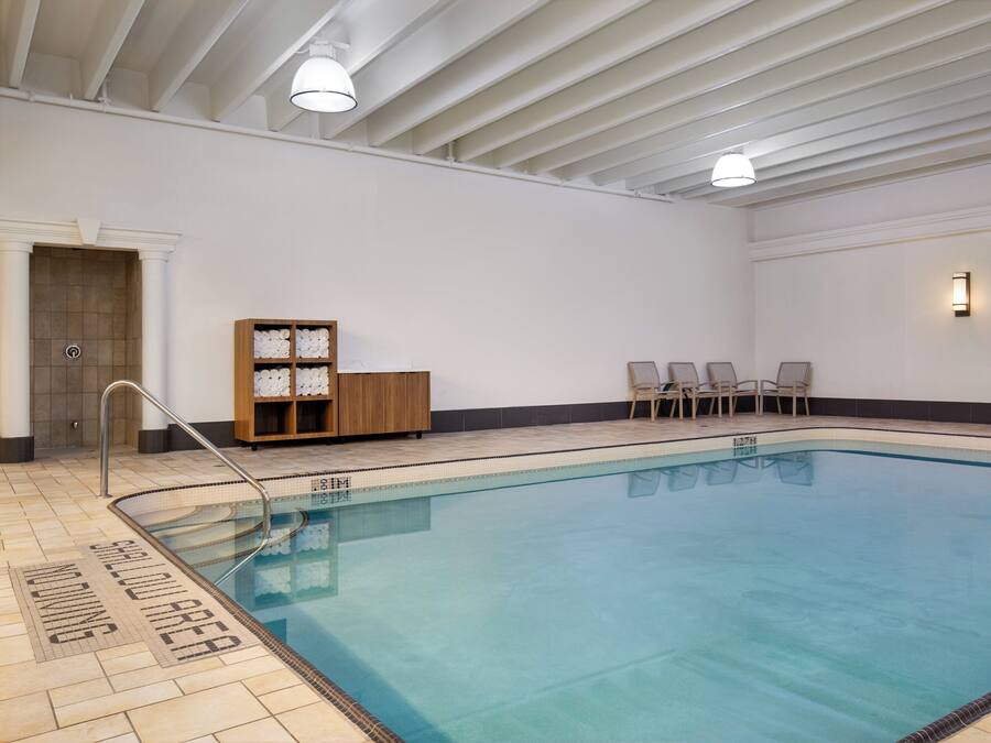 A swimming pool with clear water, a wooden cabinet with towels, and a door with a towel rack.