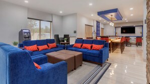 A modern living room with blue sofas and orange cushions, a flat-screen TV, and an ATM. - Comfort Inn & Suites Memphis East (Memphis)