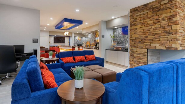 A modern living room with blue sofas, a coffee table, and a stone accent wall. - Comfort Inn & Suites Memphis East (Memphis)