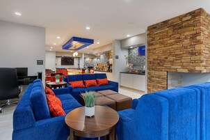 Una sala de estar moderna con sofás azules, una mesa de centro y una pared de acento de piedra.