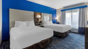 A hotel room with two beds, a large mirror, a desk with a lamp, and a window with curtains. - Comfort Inn & Suites Memphis East (Memphis)
