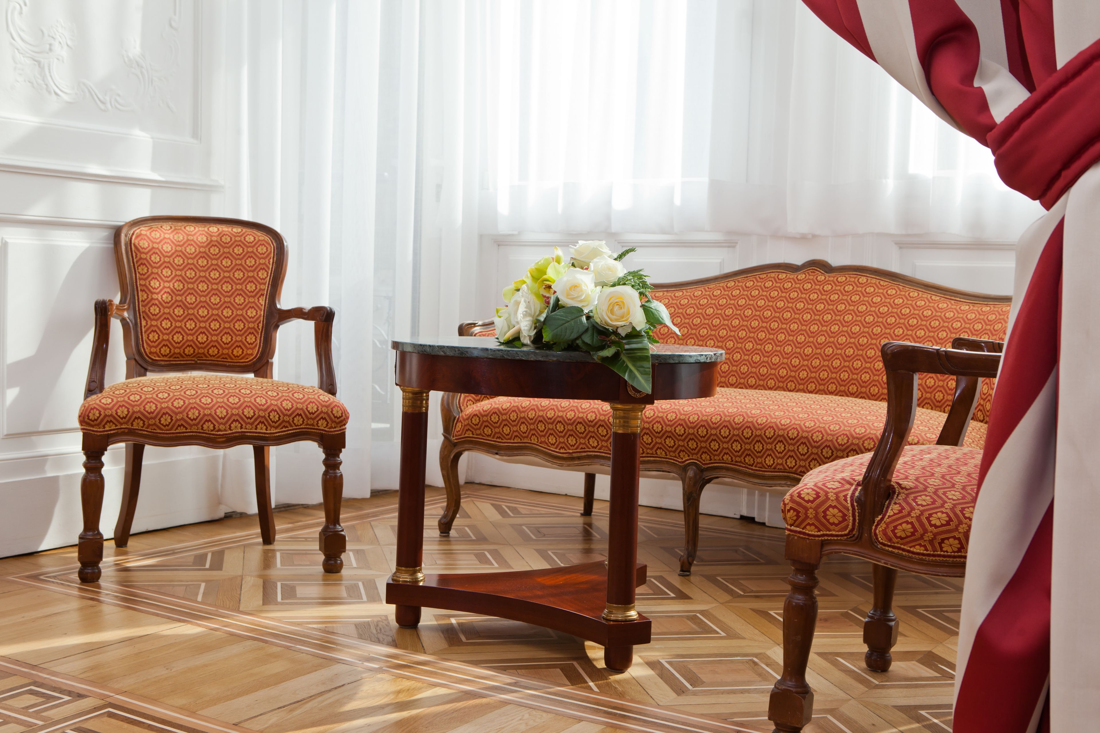 A room with a patterned sofa, a wooden table with a vase of flowers, and a patterned chair.