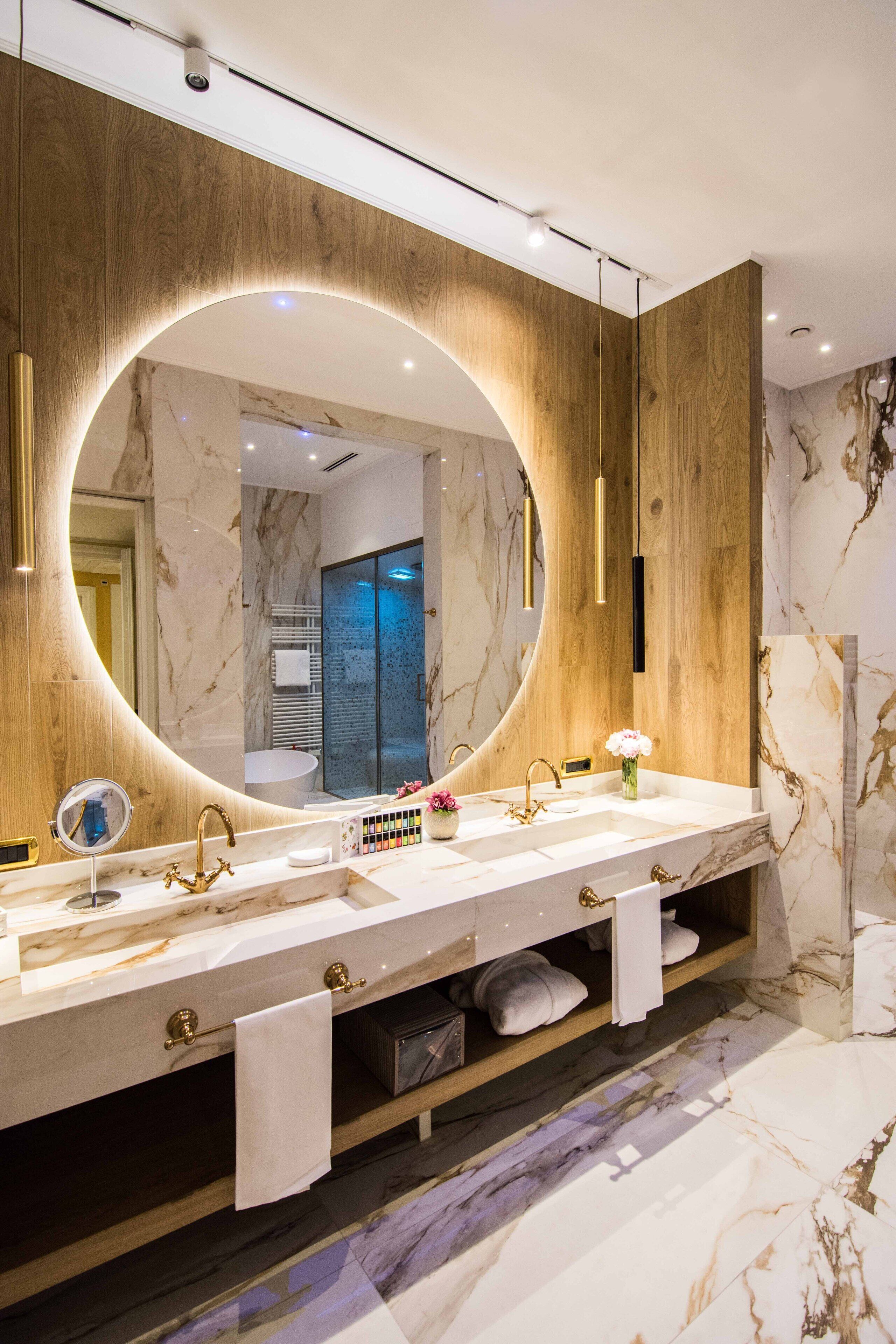 A modern bathroom with a large mirror, two sinks, and a built-in shower.