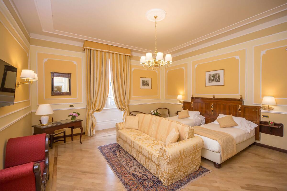 A hotel room with a bed, a sofa, a desk, and a chair.