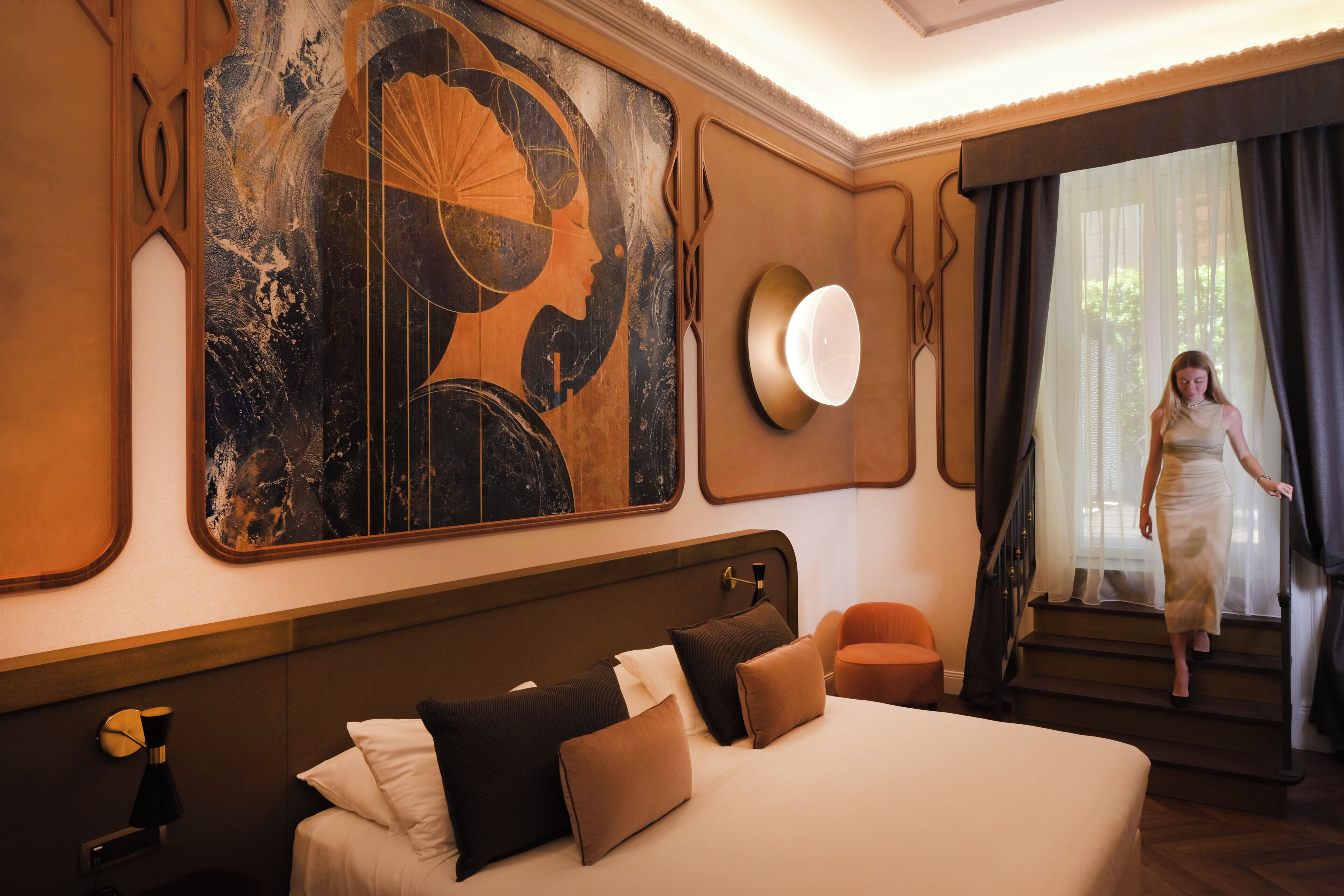 A hotel room with a large bed, a headboard with a mirror, a wall-mounted artwork, and a staircase leading to a balcony.
