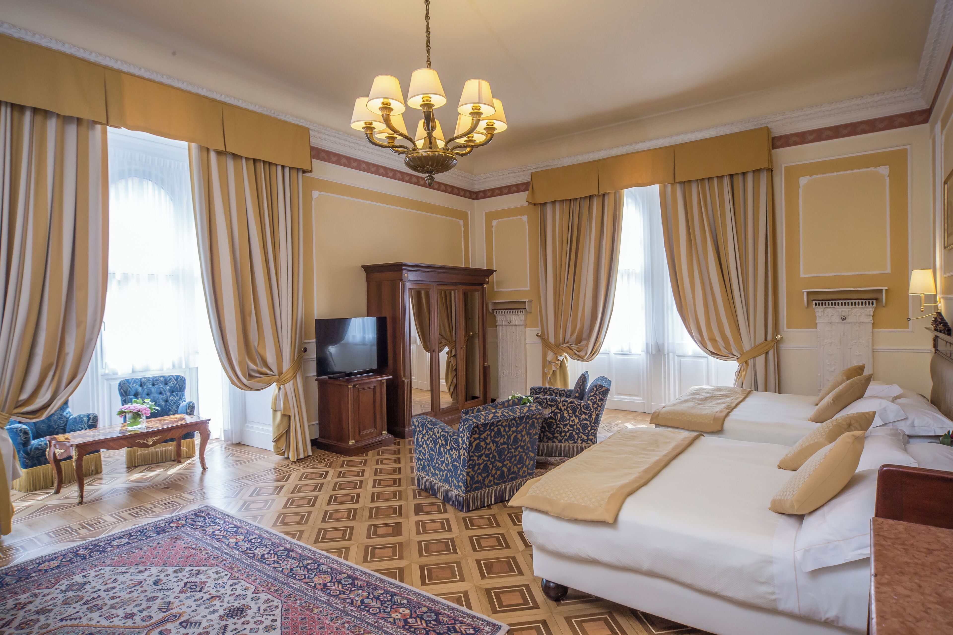 Una habitación de hotel con una cama grande, dos sillones, un televisor y una alfombra decorativa.