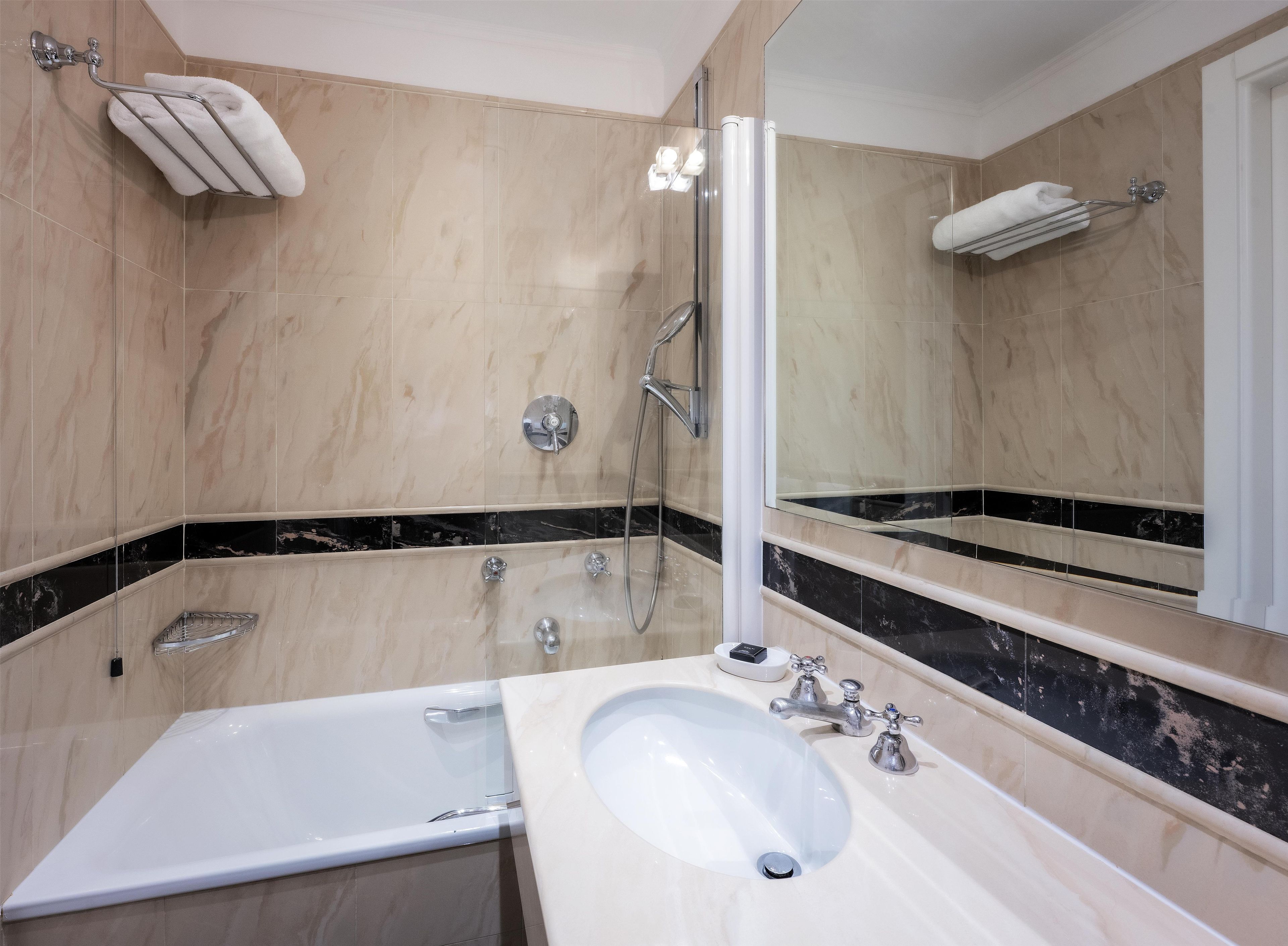 Un baño moderno con una bañera, un lavabo, una ducha y un espejo grande.