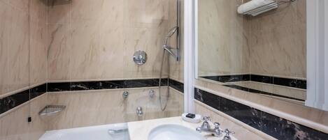 Un baño moderno con una bañera, un lavabo, una ducha y un espejo grande.