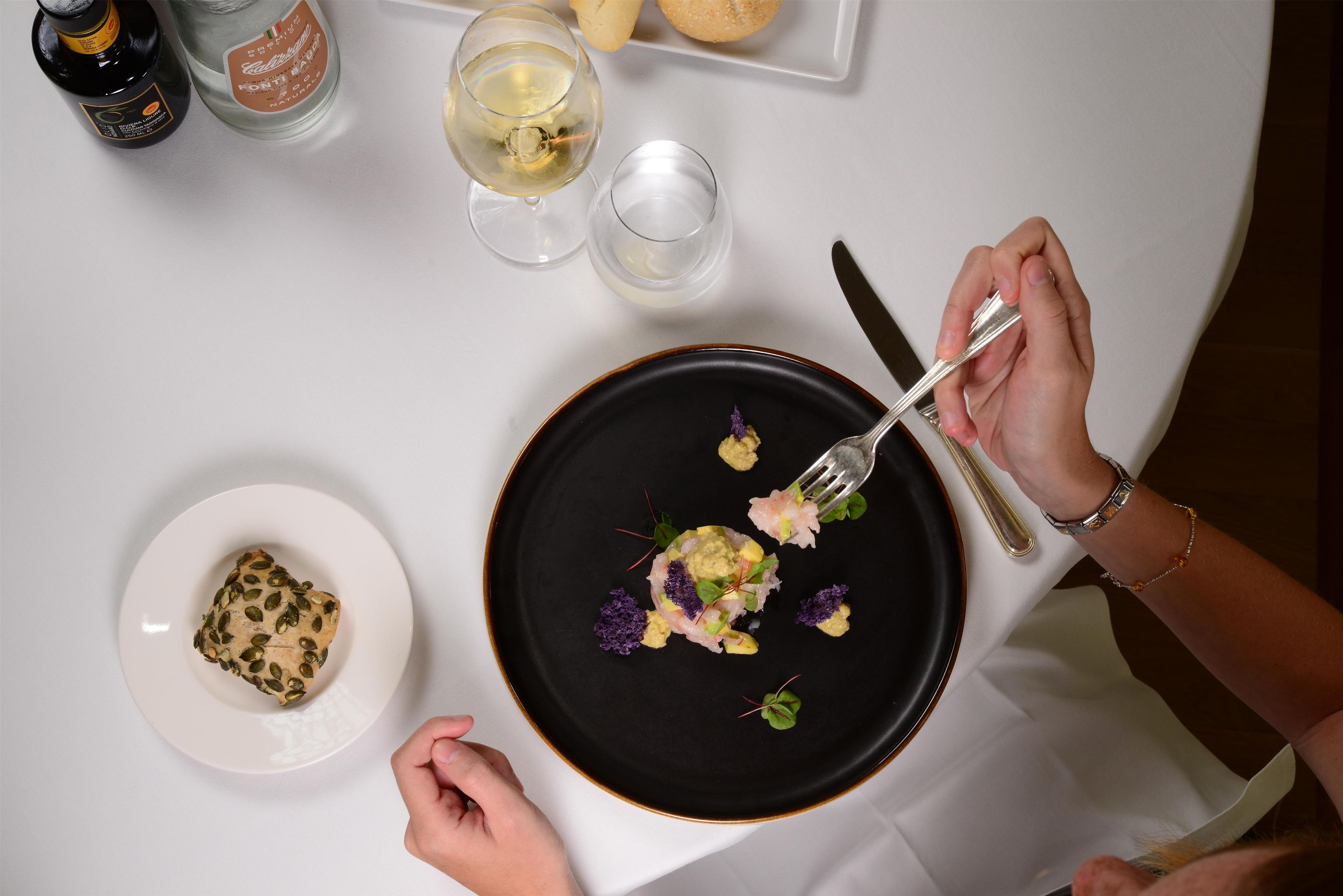 A dining table with a plate of food, a bottle of olive oil, and a glass of water.