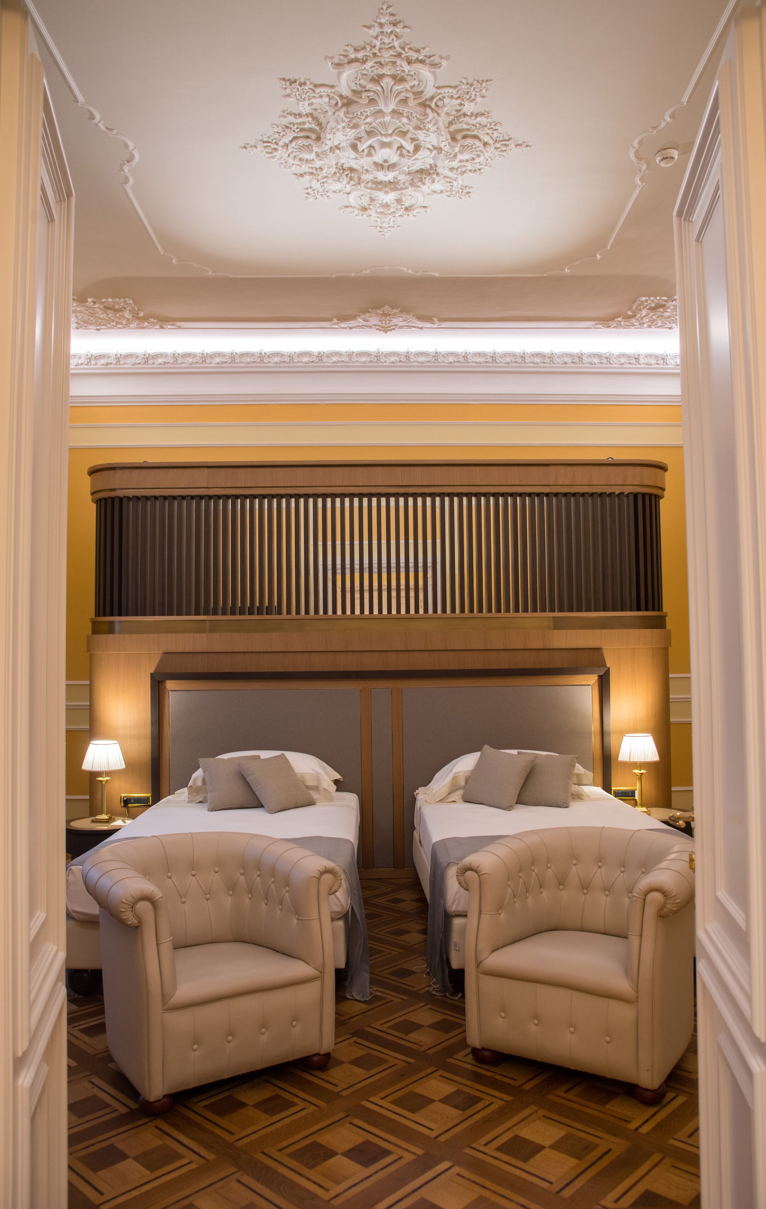 A hotel room with two beds, a chandelier, and a checkered floor.