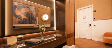 Habitación de hotel con tocador de mármol, un espejo grande, un jarrón con flores, una puerta y una silla.