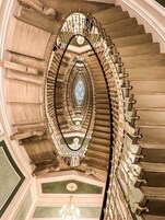 A grand staircase with ornate railings and a central glass window.