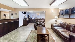 A hotel lobby with a reception desk, a leather sofa, a coffee table, and a kitchen area in the background. - Days Inn by Wyndham Jackson (Jackson)