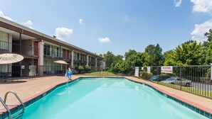 A swimming pool with a metal railing, a building with balconies, and a sign stating "NO DIVING NO LIFEGUARD". - Days Inn by Wyndham Jackson (Jackson)