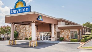A Days Inn hotel with a stone facade, a covered entrance, and a parking lot. - Days Inn by Wyndham Jackson (Jackson)