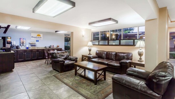 A spacious living area with leather sofas, a coffee table, and a kitchen area in the background. - Days Inn by Wyndham Jackson (Jackson)