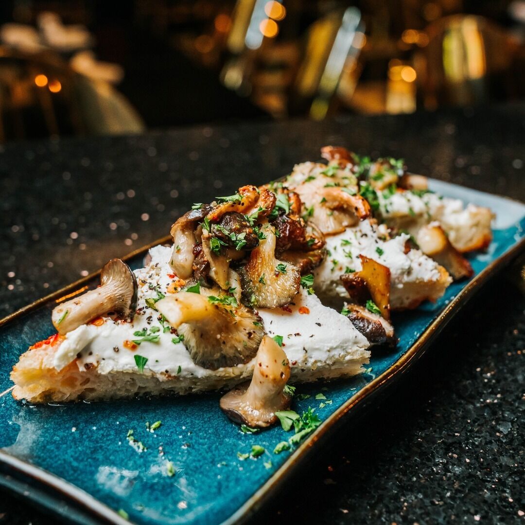 A dish with mushrooms and herbs on a blue plate.