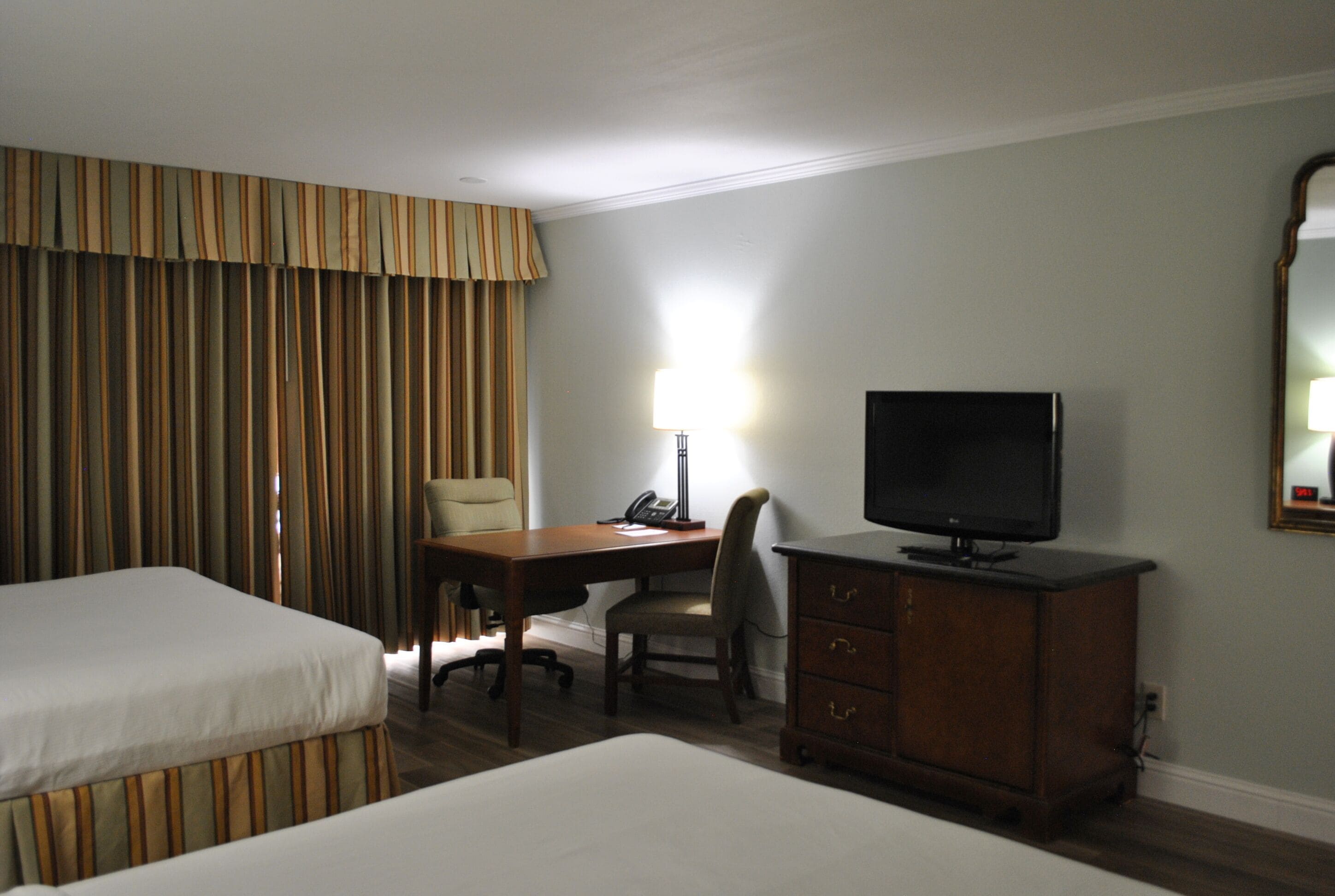 Una habitación de hotel con dos camas, un escritorio con una silla, un televisor y un aparador.