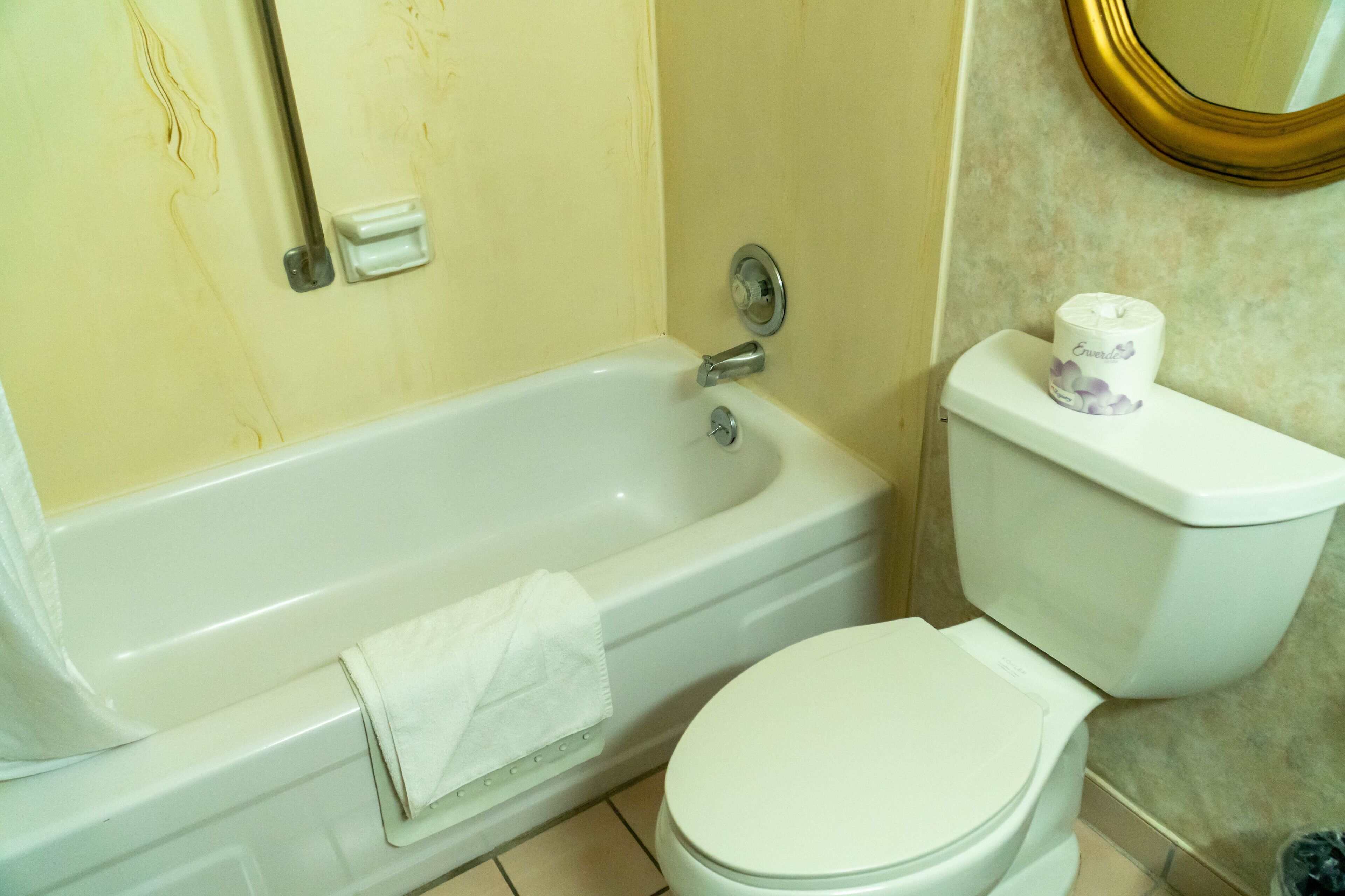 A bathroom with a bathtub, toilet, and a towel rack.
