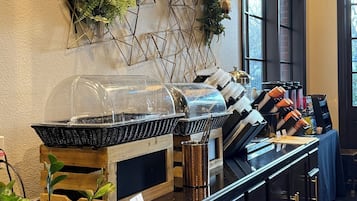 A buffet area with a grill, various food items, and decorative plants.