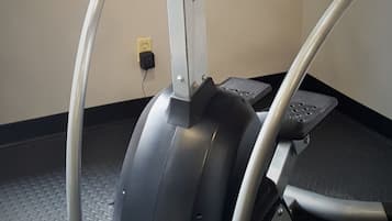 A stationary exercise bike with a red and black seat, silver frame, and a control panel with buttons.