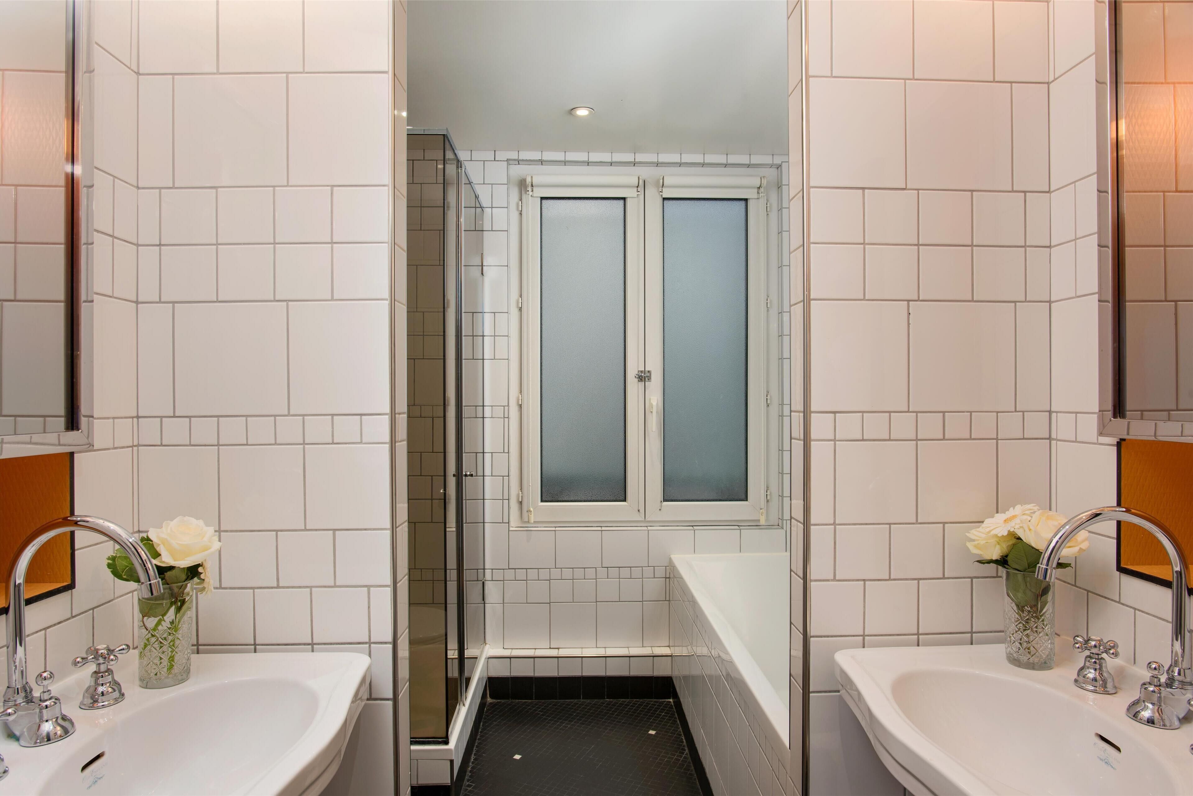 A bathroom with two sinks, a shower, and frosted glass doors.