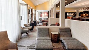 A modern lobby with seating areas, a reception desk, and a bar. - Courtyard by Marriott Cincinnati Blue Ash (Cincinnati)