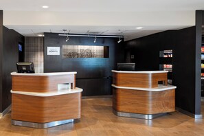 A reception area with two wooden reception desks, a digital screen, and a wall-mounted artwork. - Courtyard by Marriott Cincinnati Blue Ash (Cincinnati)