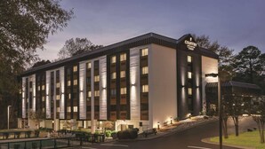 A modern hotel with a flat roof, multiple windows, and a well-lit entrance. - Country Inn & Suites by Radisson, Williamsburg East (Busch Gardens), VA (Williamsburg)